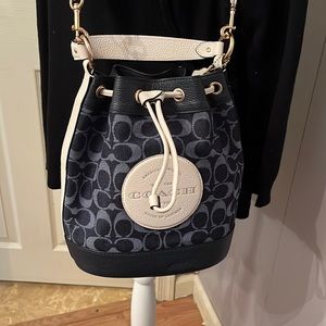 Denim Coach Dempsey logo drawstring crossbody bag with rainbow strap.